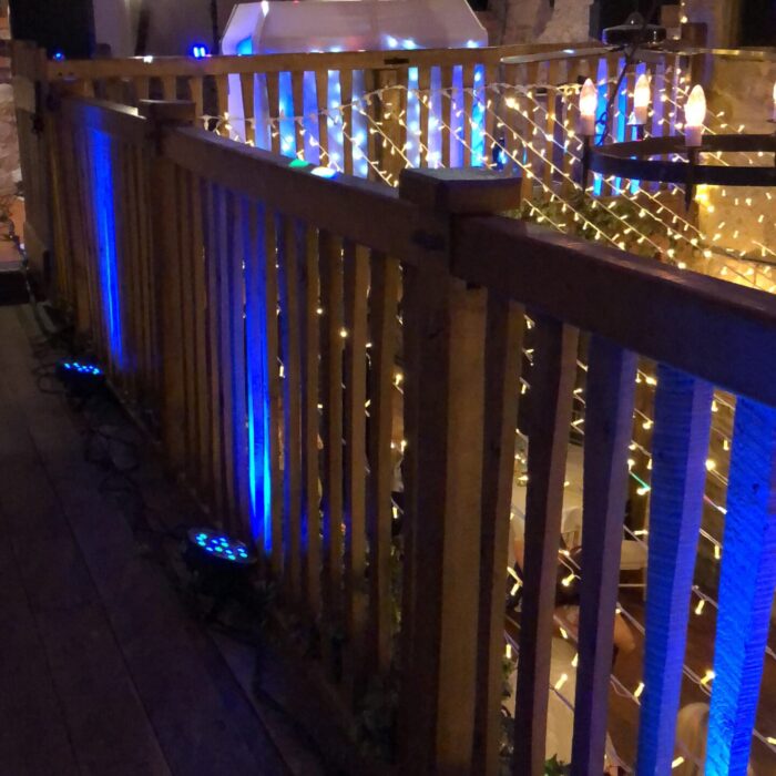 Blue uplights shine up a balcony supporting bright fairy lights