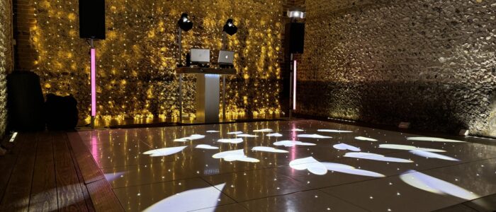 A barn space is transformed with golden fairylights on the walls, and a powerful light show