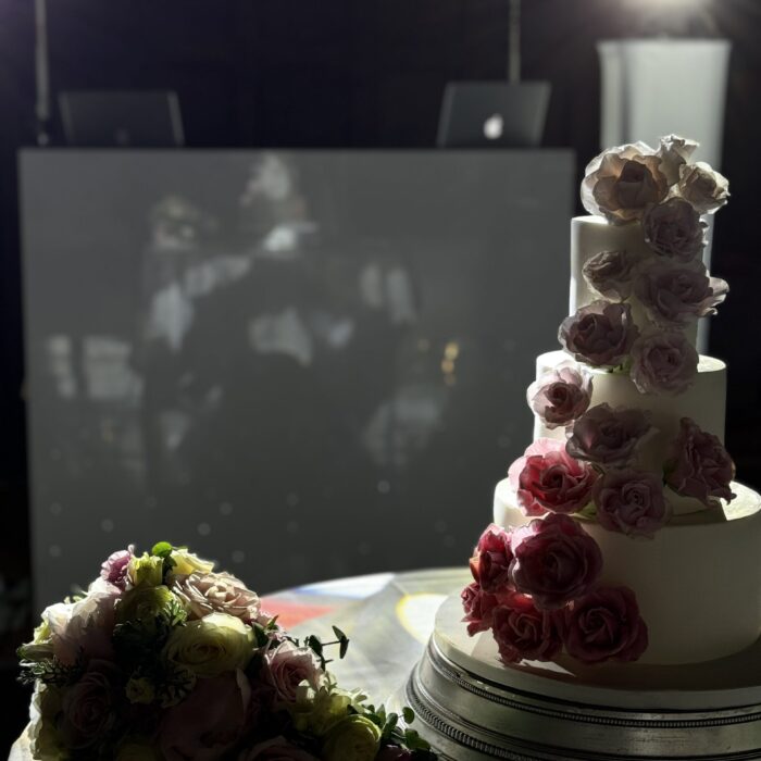 A stunning wedding cake stands bathed in white light in preparation for the evening's festivities