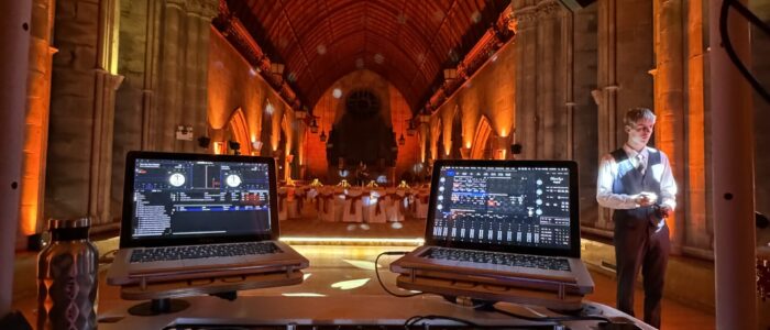 A beautiful arched roof is lit for a Wedding, with glorious colours and contrasts highlighting the space and walls whilst technical equipment fill the foreground, ready for the evening reception