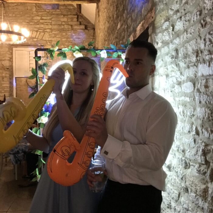 A couple play inflatable saxophone props in a photopod picture